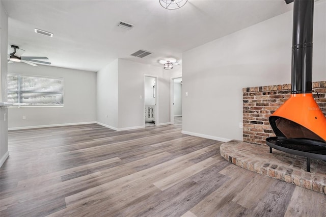 living room featuring ceiling fan, a wood stove, and light wood-type flooring