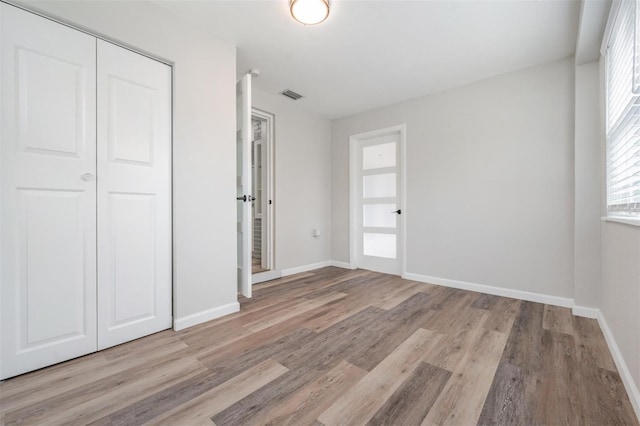 unfurnished bedroom with a closet and light wood-type flooring