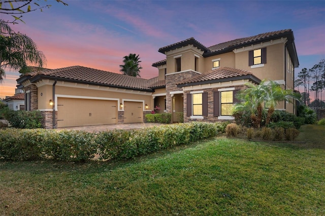 mediterranean / spanish-style home with a yard and a garage