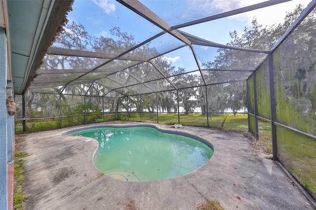 view of swimming pool featuring a lawn, a patio area, and a lanai