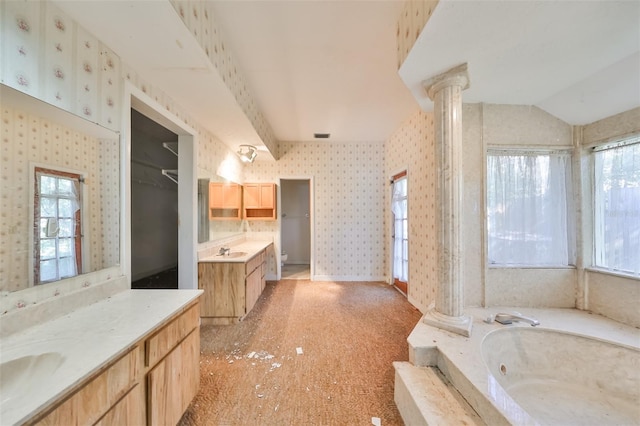 bathroom featuring vanity, lofted ceiling, a bathing tub, and ornate columns