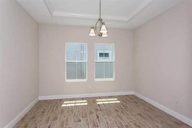 unfurnished room with a tray ceiling, a chandelier, light hardwood / wood-style floors, and ornamental molding