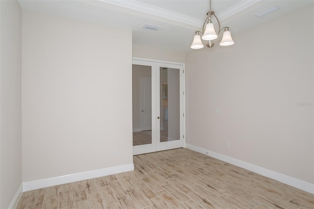 spare room featuring light hardwood / wood-style floors, french doors, and an inviting chandelier