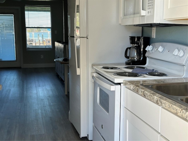 kitchen with white appliances, white cabinetry, and dark hardwood / wood-style flooring