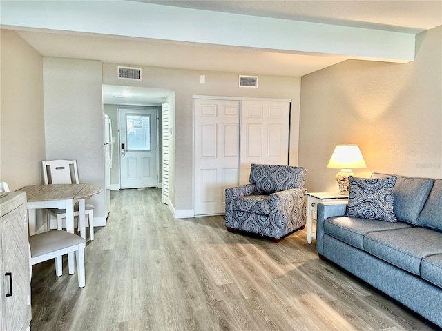 living room featuring beamed ceiling and light wood-type flooring