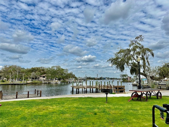 view of dock with a lawn and a water view