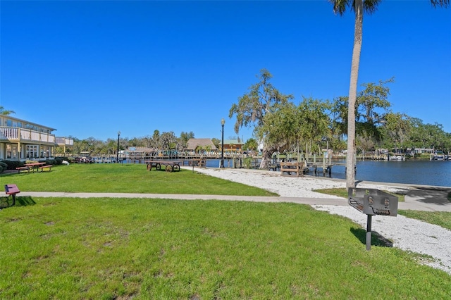 view of property's community with a water view and a lawn