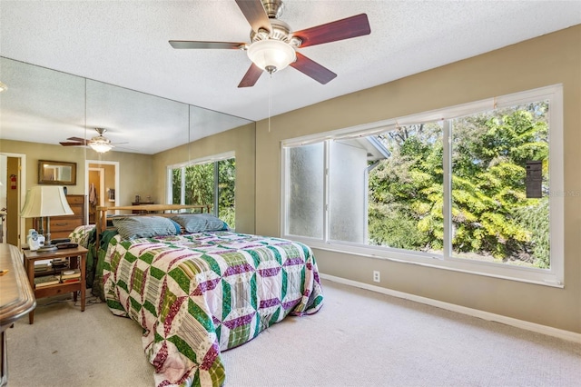 carpeted bedroom featuring ceiling fan and a textured ceiling