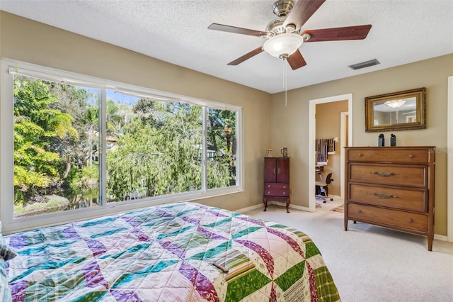 carpeted bedroom with ceiling fan and a textured ceiling