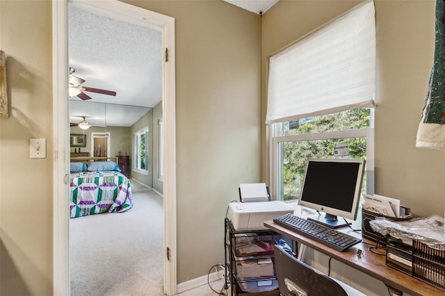 office space with plenty of natural light, a textured ceiling, light colored carpet, and ceiling fan