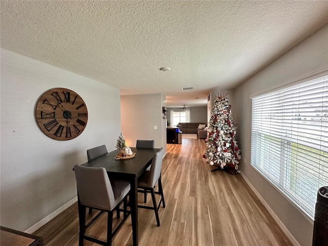 dining area with visible vents, wood finished floors, baseboards, and a textured ceiling