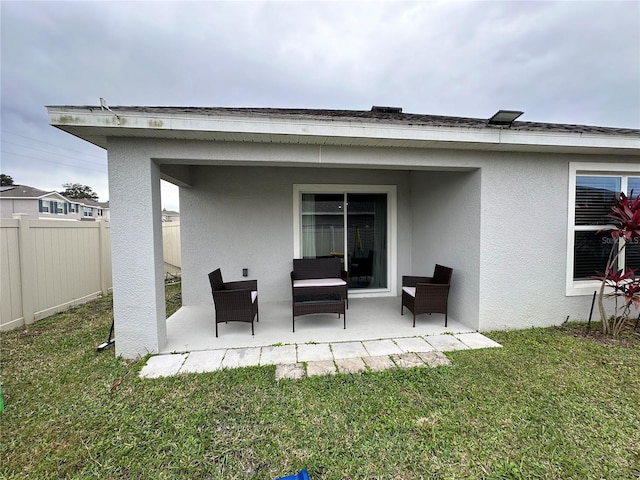 back of house with stucco siding, a lawn, a patio, and fence