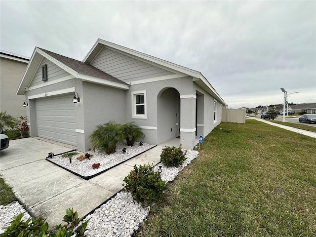 ranch-style house with a front lawn, concrete driveway, roof with shingles, stucco siding, and an attached garage