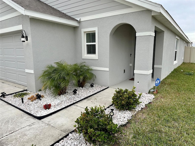 entrance to property with stucco siding and an attached garage