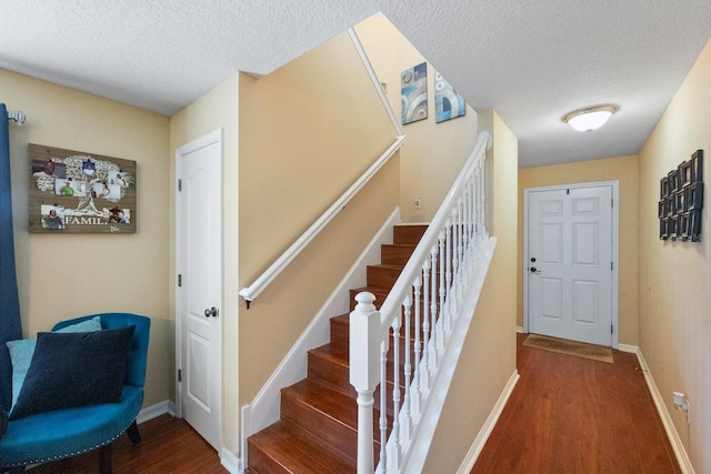 stairway featuring a textured ceiling and dark hardwood / wood-style floors