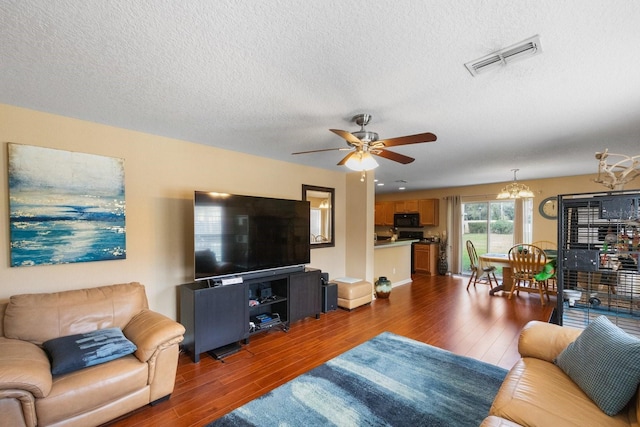 living room featuring a textured ceiling, ceiling fan with notable chandelier, and dark hardwood / wood-style flooring