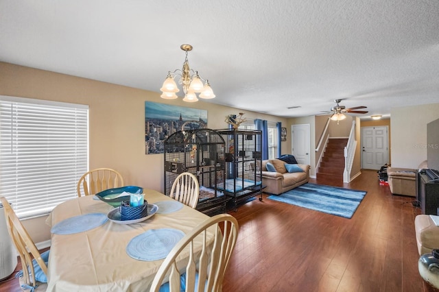 dining room with plenty of natural light, a textured ceiling, ceiling fan with notable chandelier, and dark wood-type flooring