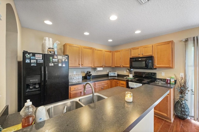 kitchen featuring dark hardwood / wood-style flooring, a textured ceiling, black appliances, and sink