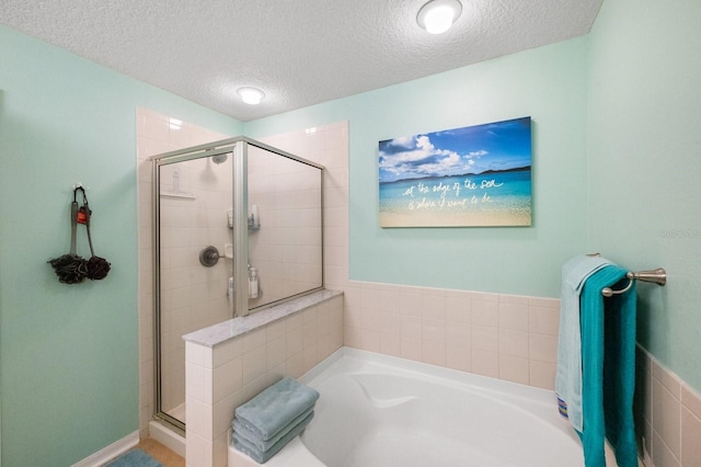 bathroom featuring a textured ceiling and separate shower and tub