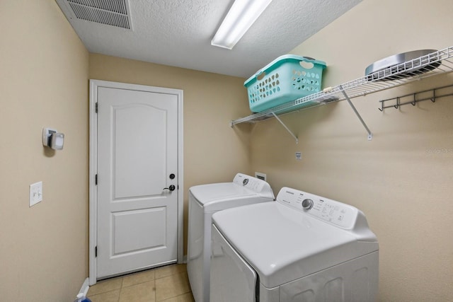 laundry area featuring hookup for a washing machine, a textured ceiling, separate washer and dryer, and light tile floors