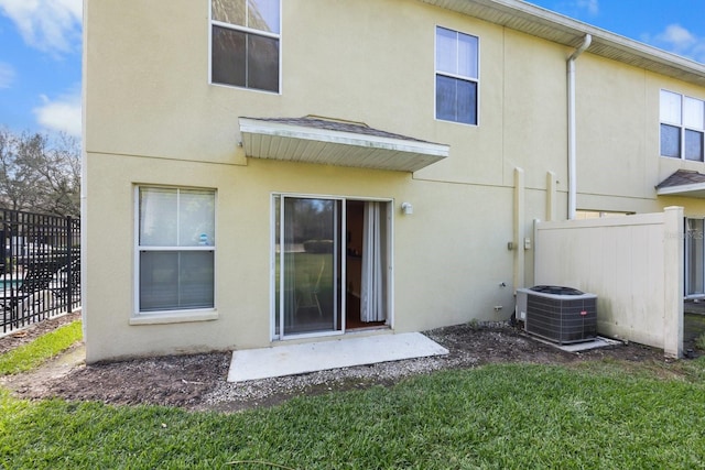 rear view of property featuring a lawn and central air condition unit