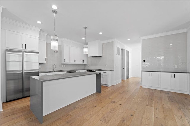 kitchen featuring light hardwood / wood-style floors, white cabinetry, stainless steel appliances, and hanging light fixtures