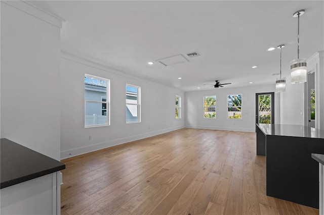 unfurnished living room with ceiling fan, light wood-type flooring, and ornamental molding