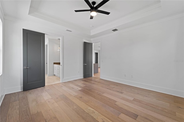 unfurnished bedroom featuring a tray ceiling, ceiling fan, and light hardwood / wood-style floors