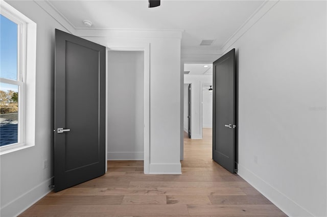 corridor with light hardwood / wood-style floors and crown molding