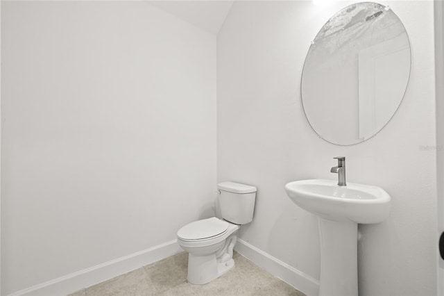 bathroom with toilet, sink, and tile patterned flooring