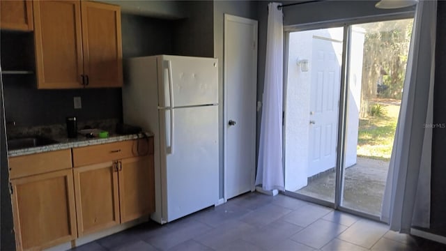 kitchen with tile patterned floors, white refrigerator, and sink