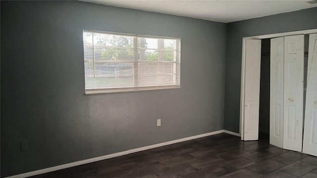 unfurnished bedroom featuring a closet and dark tile patterned flooring