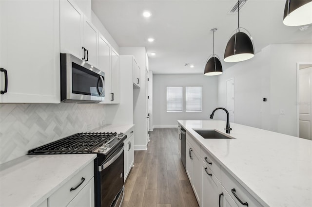 kitchen featuring pendant lighting, appliances with stainless steel finishes, sink, and white cabinets