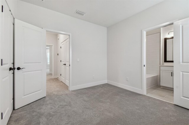 unfurnished bedroom with connected bathroom and light carpet