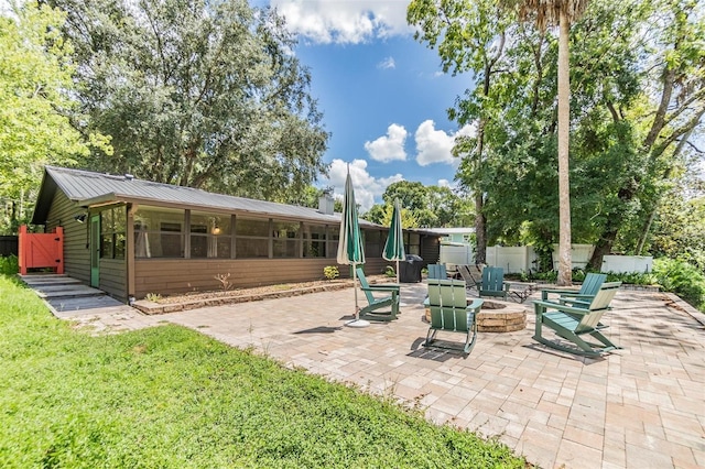 view of patio with an outdoor fire pit and a sunroom