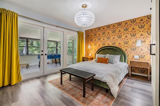 bedroom featuring french doors, a notable chandelier, access to outside, and wood-type flooring