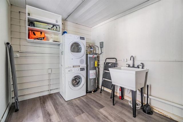 laundry room with stacked washer / drying machine, electric water heater, and hardwood / wood-style flooring