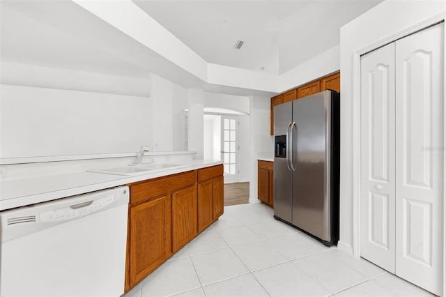 kitchen with light tile floors, white dishwasher, stainless steel fridge, and sink