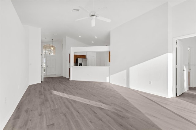 spare room featuring a high ceiling, ceiling fan, and light hardwood / wood-style flooring