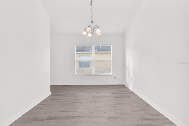 empty room with an inviting chandelier and light hardwood / wood-style floors