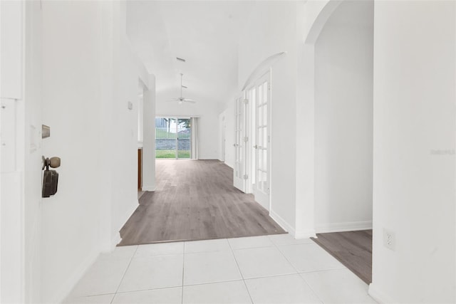 hallway featuring vaulted ceiling, light hardwood / wood-style floors, and french doors