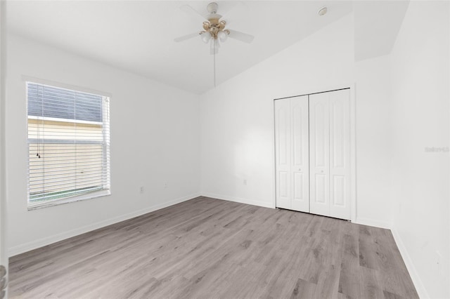 unfurnished bedroom with a closet, light hardwood / wood-style floors, ceiling fan, and vaulted ceiling