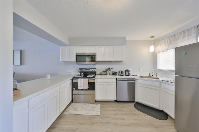 kitchen with hanging light fixtures, light wood-type flooring, white cabinetry, and stainless steel appliances