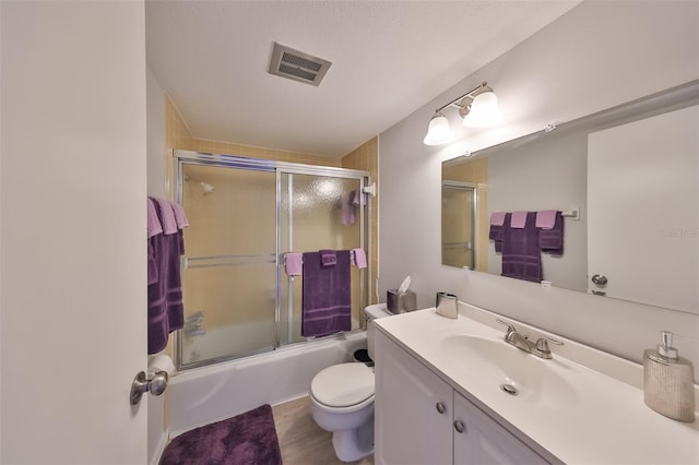 full bathroom featuring toilet, oversized vanity, a textured ceiling, enclosed tub / shower combo, and tile floors