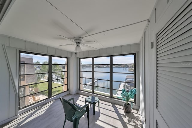 sunroom / solarium with ceiling fan and a water view