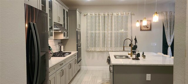 kitchen featuring under cabinet range hood, appliances with stainless steel finishes, gray cabinetry, and a sink