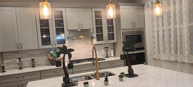 kitchen featuring under cabinet range hood, glass insert cabinets, appliances with stainless steel finishes, and gray cabinets