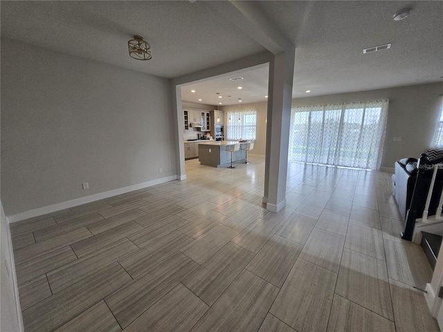 unfurnished living room with visible vents, baseboards, wood finish floors, recessed lighting, and a textured ceiling