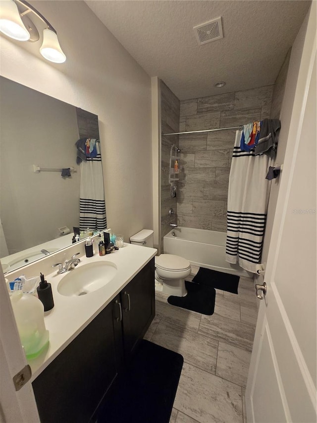 full bathroom with visible vents, toilet, vanity, shower / tub combo with curtain, and a textured ceiling