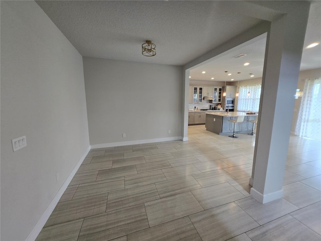 unfurnished living room with recessed lighting, baseboards, and a textured ceiling